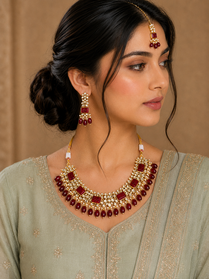 Maroon kundan necklace with pearl clusters, bead drops, matching earrings and maang tikka